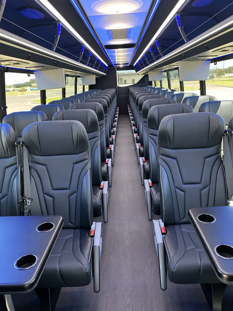 Coach aisle with leather seats, tables and blue ceiling lights