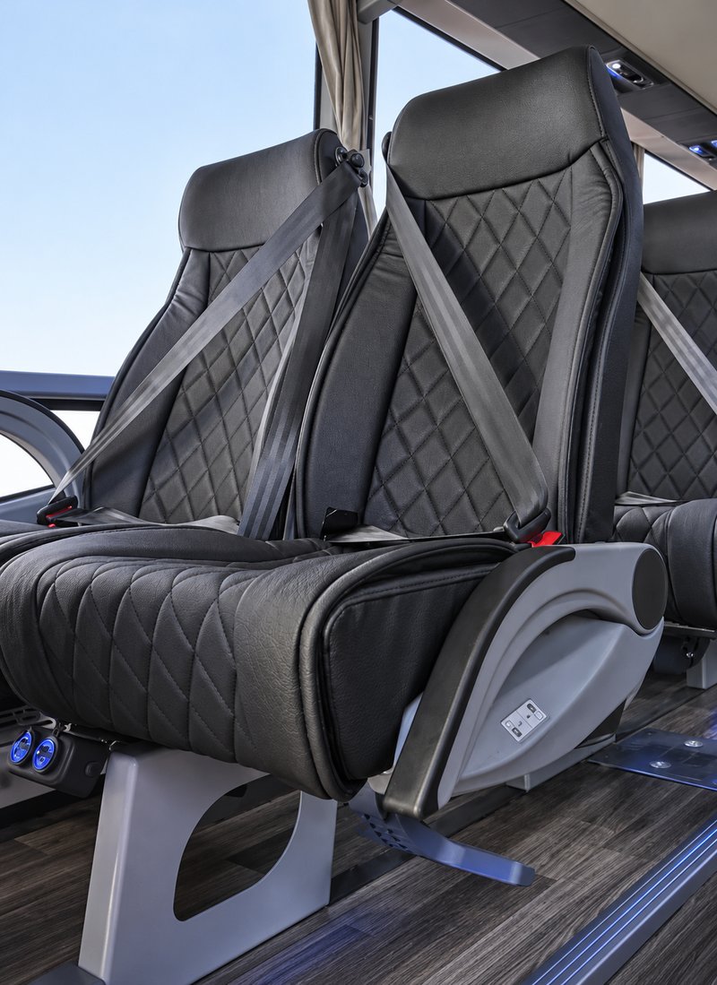 Diamond-stitched coach seats with seatbelts and nearby outlets